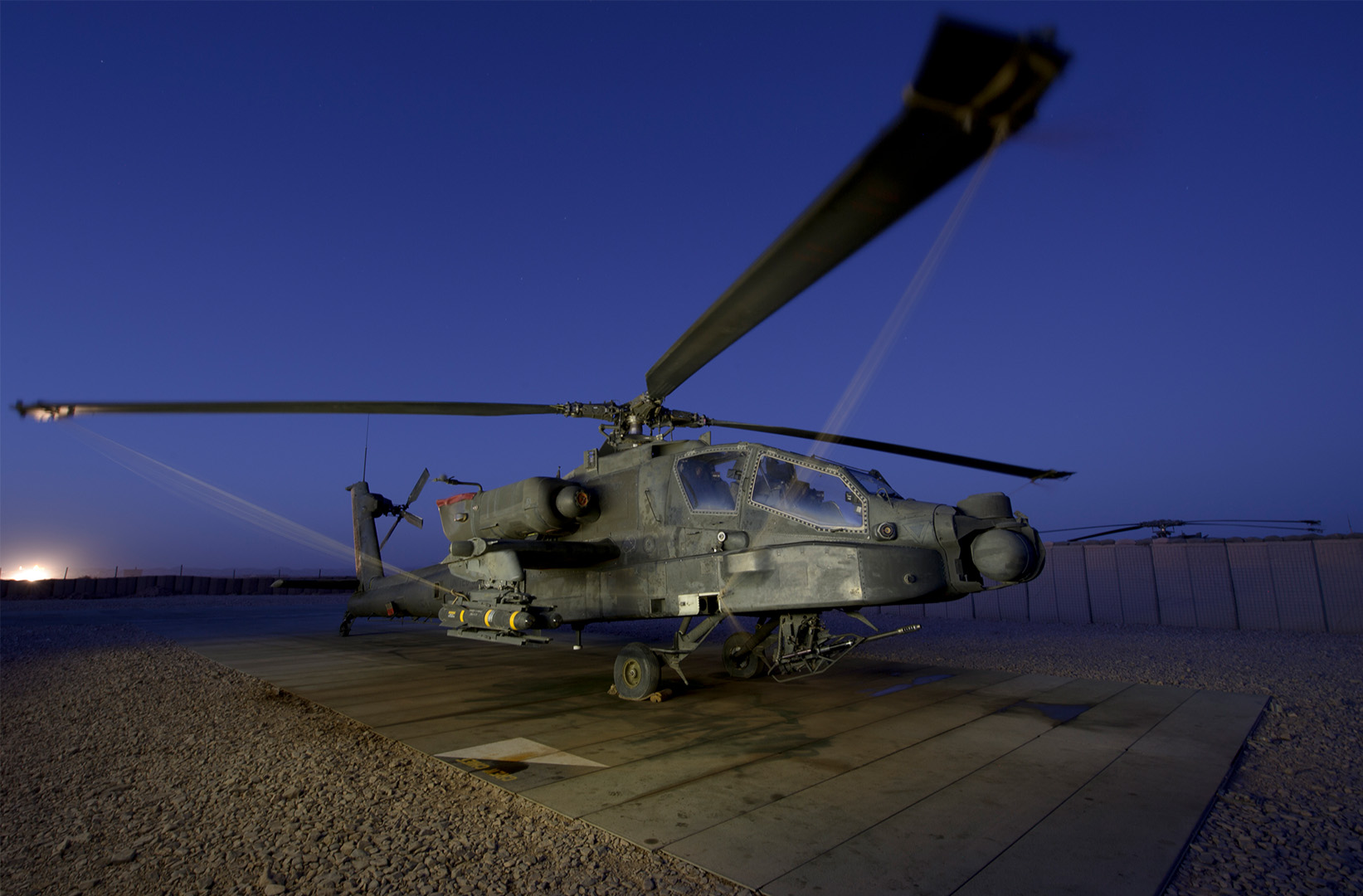 AH-64 Apache attack helicopter on a landing pad at night