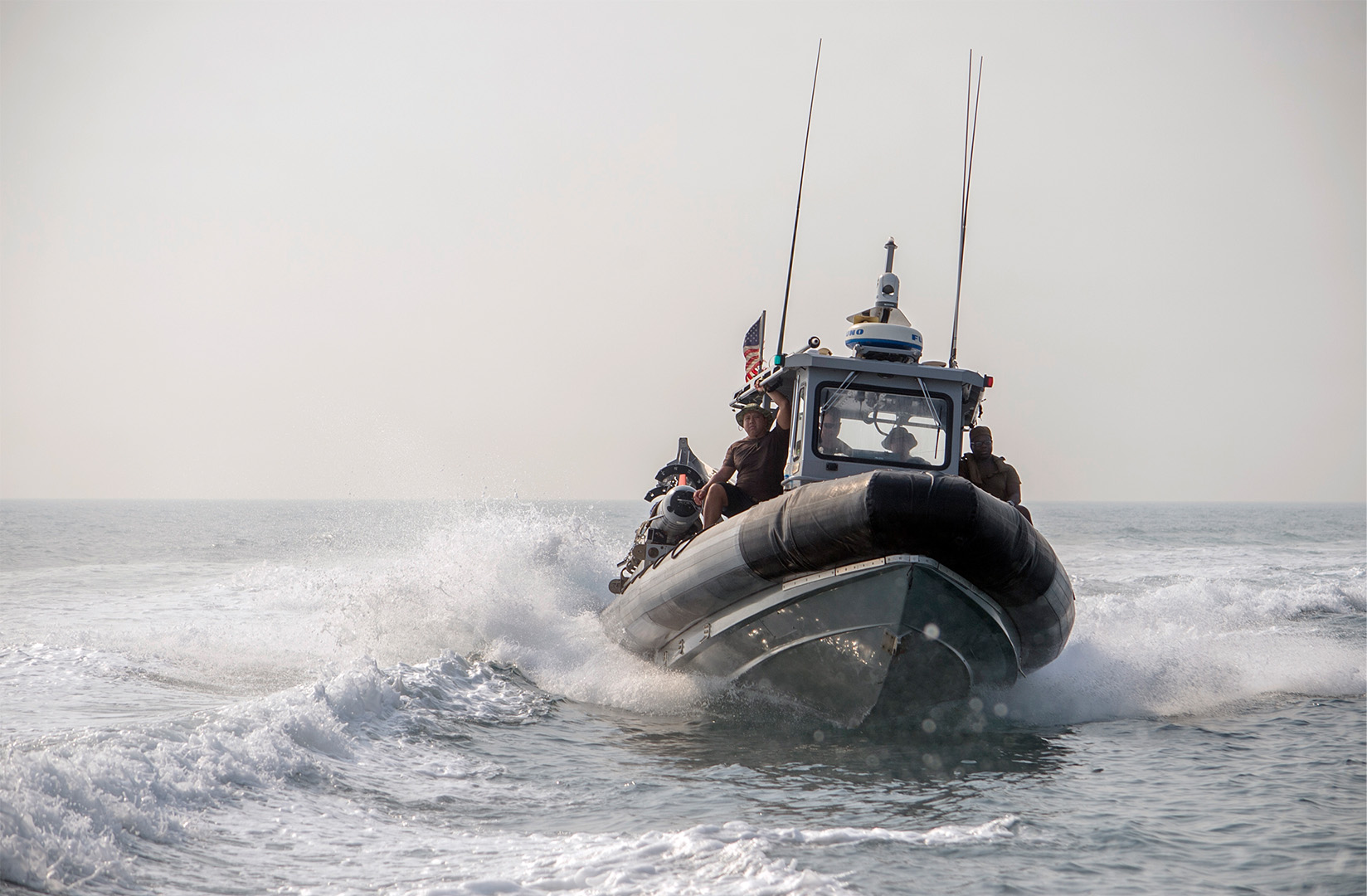American military boat racing across the water with soldiers aboard