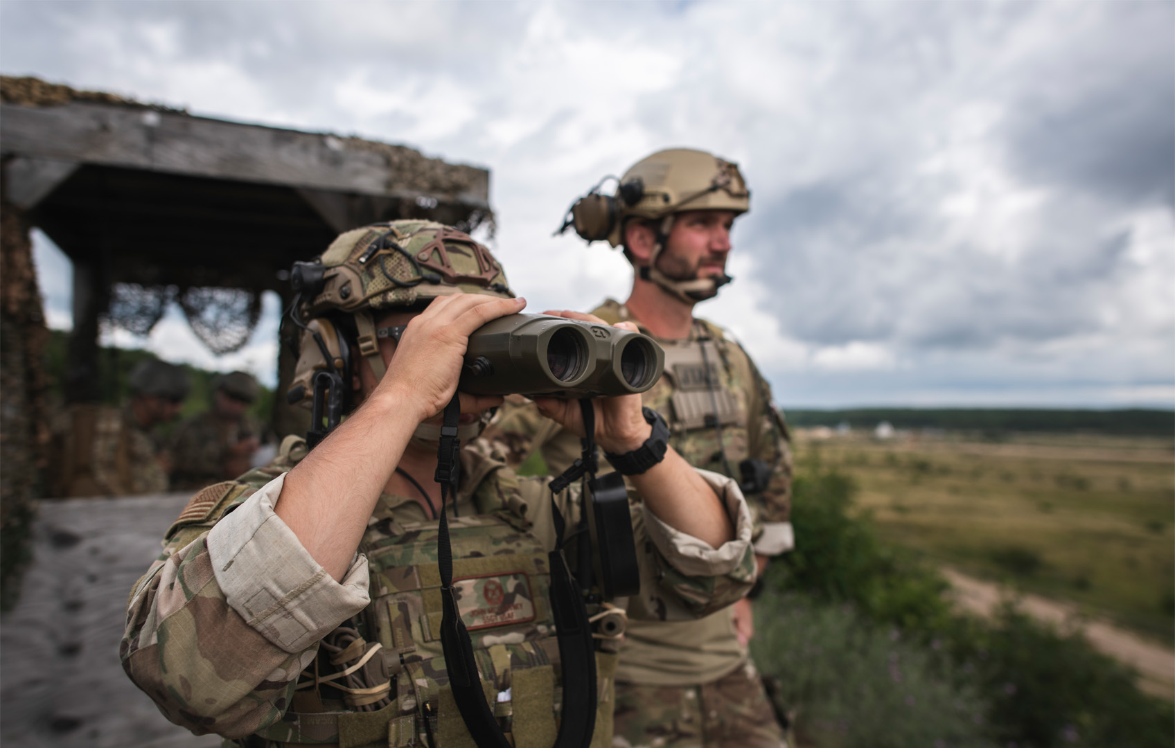 Two soldiers looking through binoculars on a mission