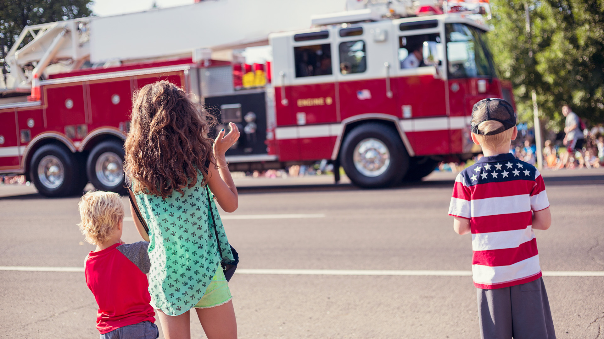 Children clapping hands while watching a firetruck drive past