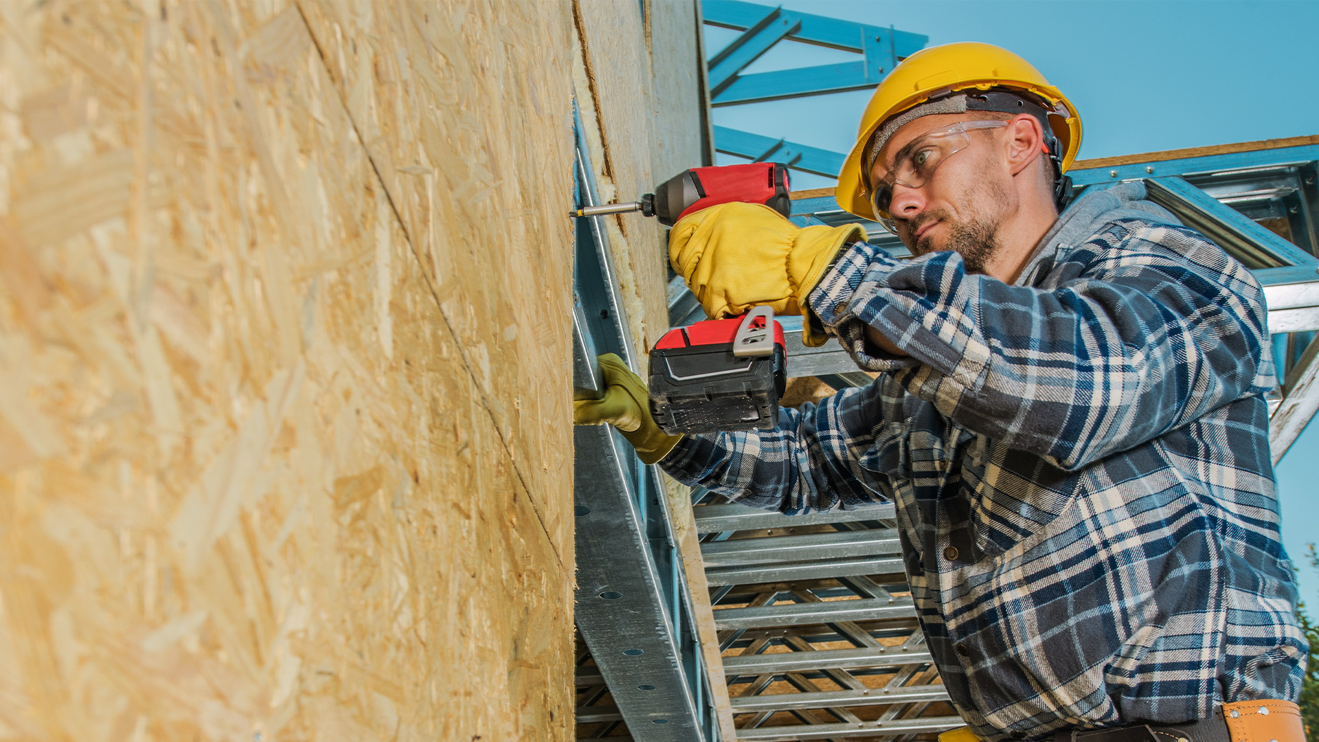 Construction worker drilling hole into plywood