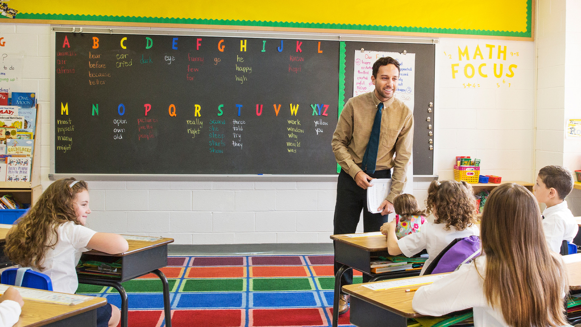 Male teacher instructing students from the front of the class